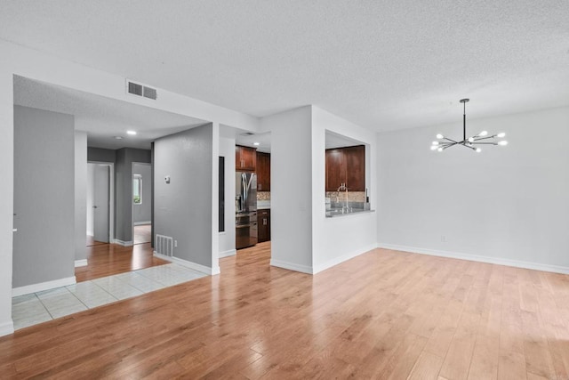 992 Lupine Hills Dr Unit 98, Vista, CA 92081 - unfurnished living room featuring a chandelier, light wood-style floors, a textured ceiling, and baseboards
