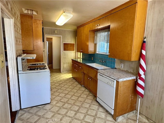 kitchen featuring light floors, white appliances, brown cabinets, and a sink