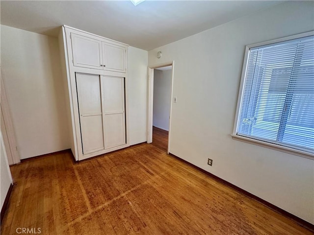 unfurnished bedroom with a closet, baseboards, and wood finished floors