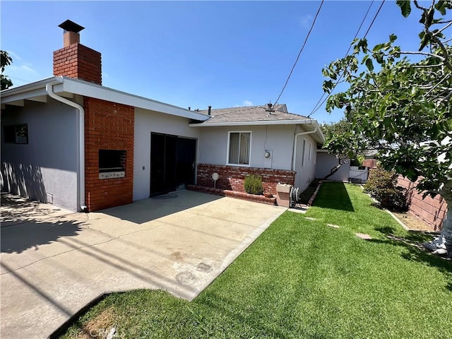 view of front facade featuring a chimney, brick siding, a patio area, stucco siding, and a front lawn