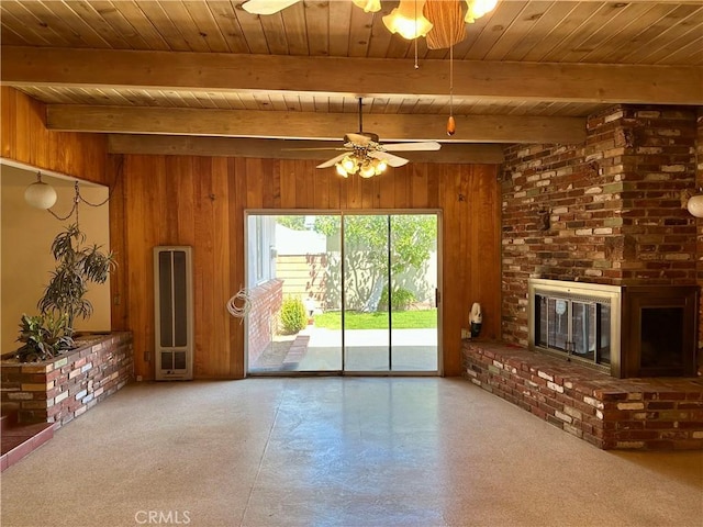 unfurnished living room featuring a ceiling fan, a heating unit, wooden ceiling, wooden walls, and a brick fireplace