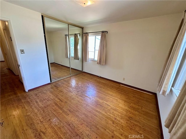 unfurnished bedroom with baseboards, a closet, and wood finished floors