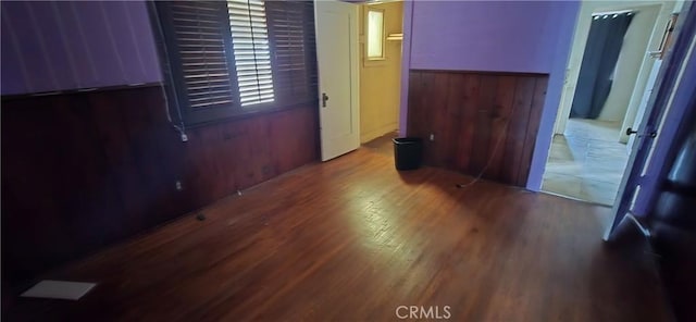 unfurnished room featuring a wainscoted wall, wood walls, and wood finished floors