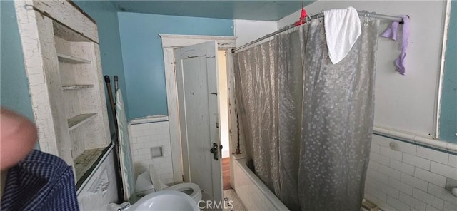 full bathroom with wainscoting, tile walls, and toilet
