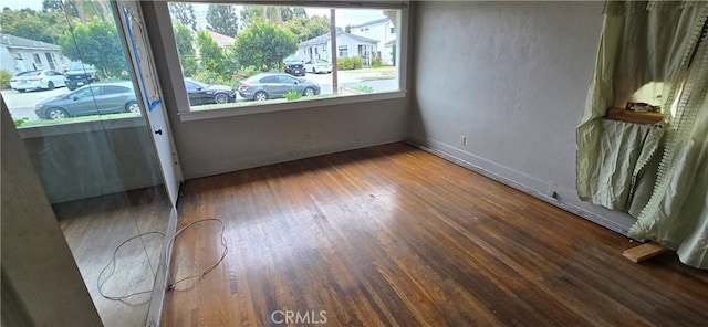 spare room with baseboards and wood finished floors
