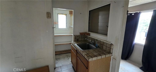kitchen featuring tile counters, a healthy amount of sunlight, and a sink