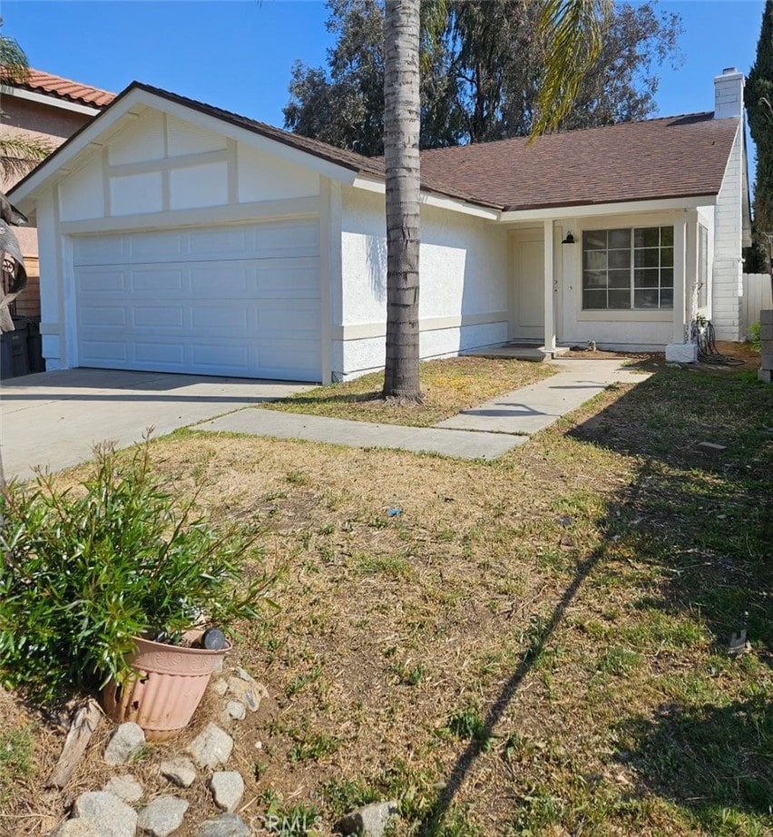 single story home featuring stucco siding, driveway, a chimney, and a garage