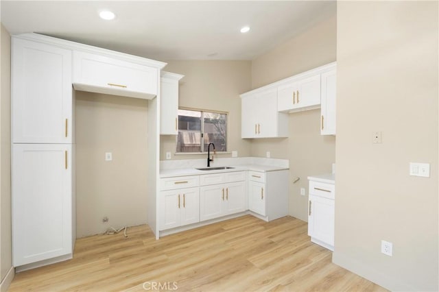 25815 Basil Ct, Moreno Valley, CA 92553 - kitchen with a sink, light wood-style flooring, white cabinetry, recessed lighting, and light countertops