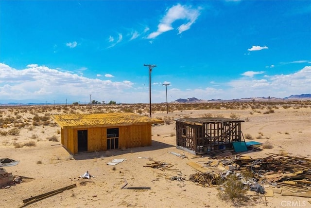 view of outbuilding with a rural view, an outbuilding, a desert view, and a mountain view