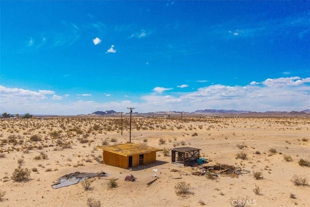 view of yard featuring a mountain view, a desert view, a rural view, and an outdoor structure