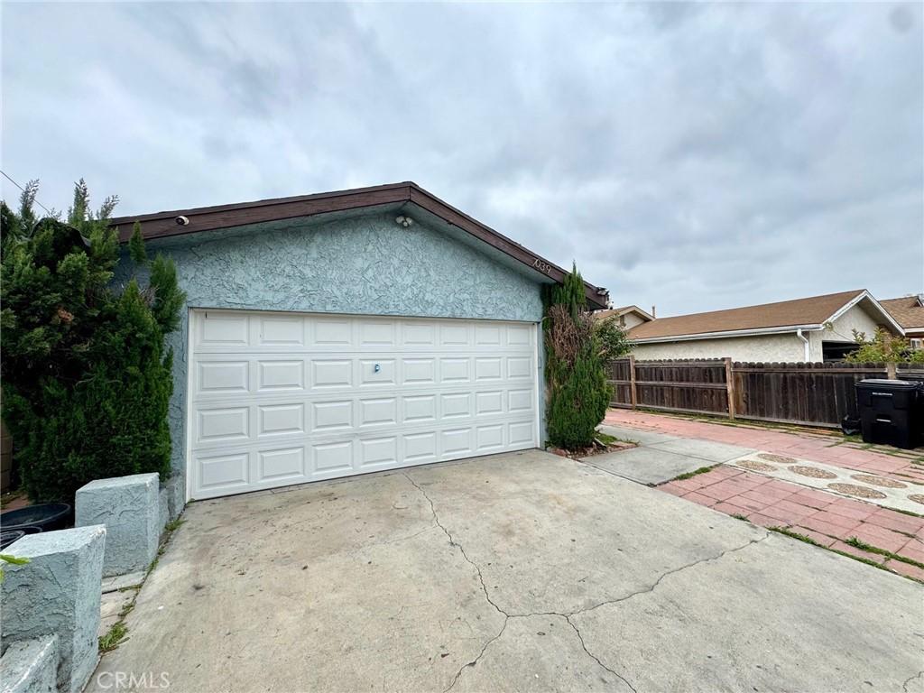 garage with concrete driveway and fence