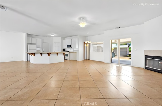 21683 Ramona Rd, Apple Valley, CA 92307 - unfurnished living room with a tiled fireplace, light tile patterned flooring, and visible vents