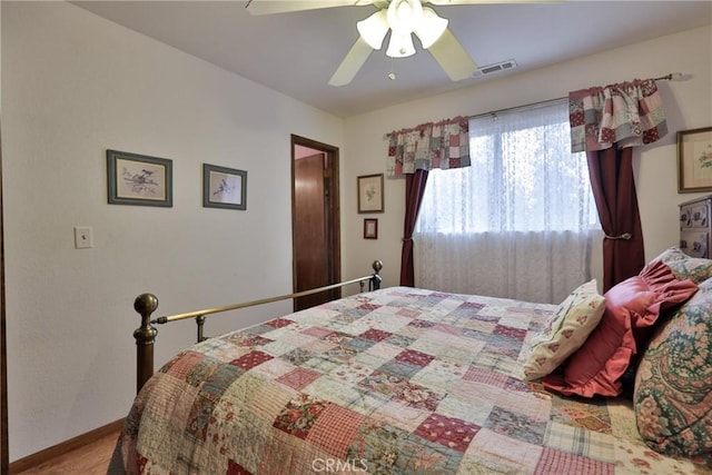 bedroom with baseboards, a ceiling fan, visible vents, and wood finished floors