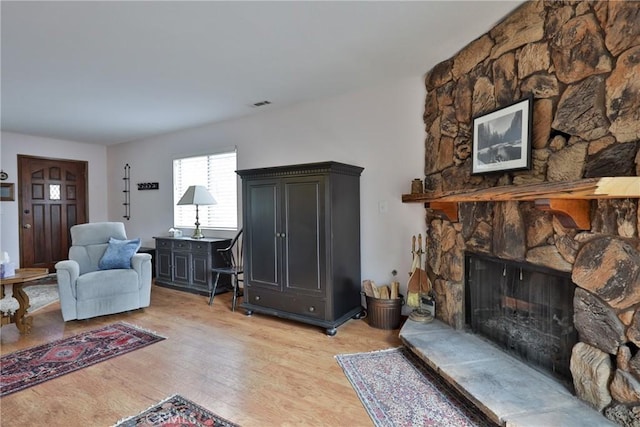 living area with a fireplace, visible vents, and light wood-style floors
