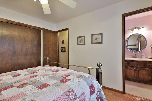 bedroom featuring ensuite bathroom, a closet, a ceiling fan, baseboards, and light wood-style floors