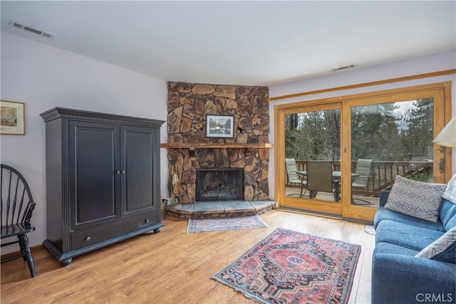 living area featuring light wood-type flooring, visible vents, and a fireplace