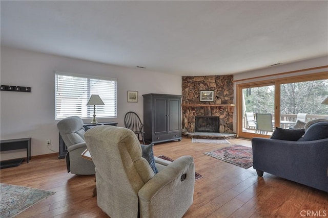 living room with a stone fireplace and light wood-style floors