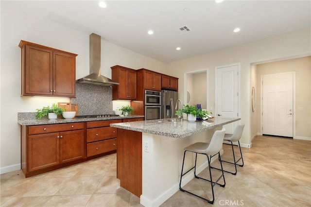 149 Luneta Ln, Rancho Mission Viejo, CA 92694 - kitchen with stainless steel appliances, a kitchen island with sink, visible vents, wall chimney range hood, and light stone counters