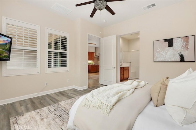 bedroom with connected bathroom, visible vents, wood finished floors, and baseboards