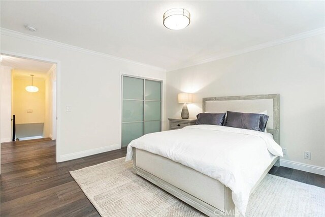 bedroom featuring a closet, dark wood finished floors, baseboards, and ornamental molding