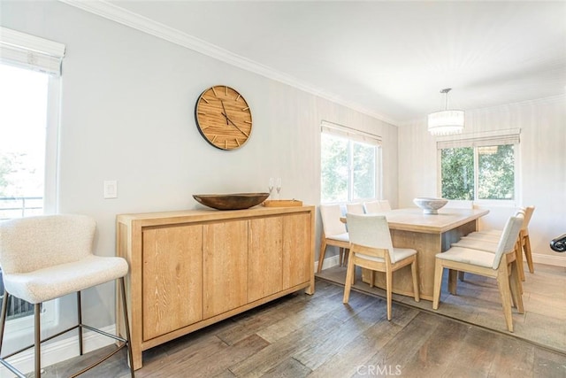 dining space with crown molding, baseboards, and wood finished floors