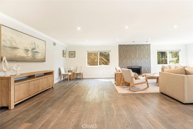 living area with recessed lighting, a high end fireplace, crown molding, and wood finished floors
