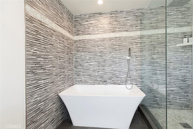 bathroom with tile patterned flooring, tile walls, and a freestanding tub
