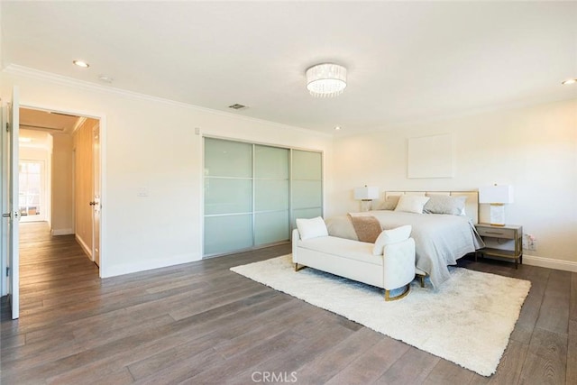 bedroom featuring a closet, dark wood-type flooring, visible vents, crown molding, and baseboards