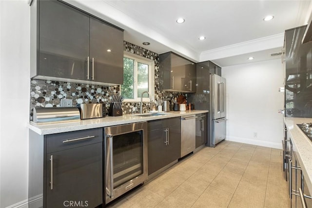 kitchen featuring a sink, stainless steel appliances, baseboards, tasteful backsplash, and wine cooler
