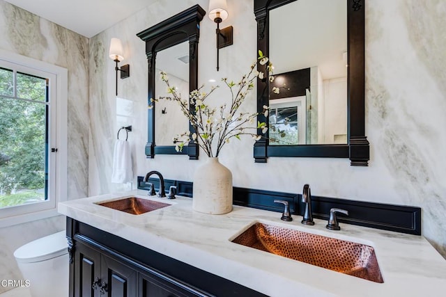 full bathroom featuring a sink, double vanity, and toilet