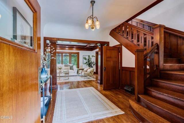 foyer entrance with a chandelier, stairway, wood finished floors, and wood walls