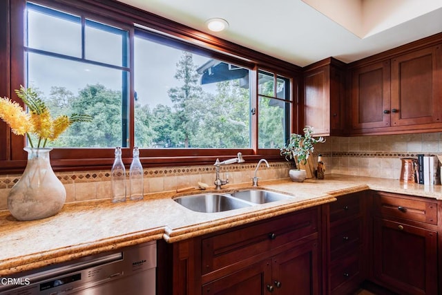 kitchen featuring dishwasher, light stone counters, tasteful backsplash, and a sink