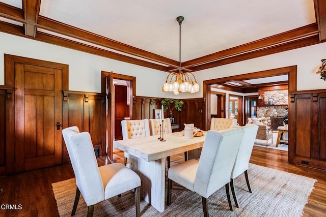 dining space featuring wood finished floors, coffered ceiling, beam ceiling, crown molding, and a chandelier