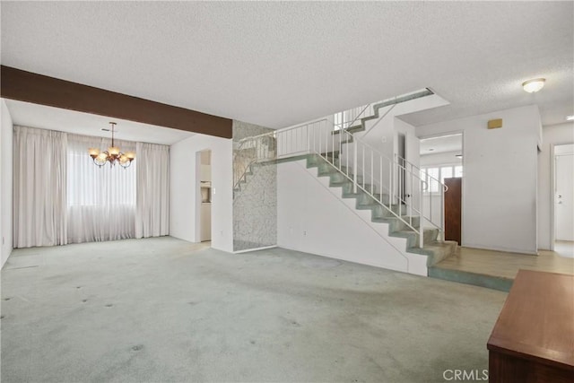 unfurnished living room with carpet, a textured ceiling, a chandelier, and stairs