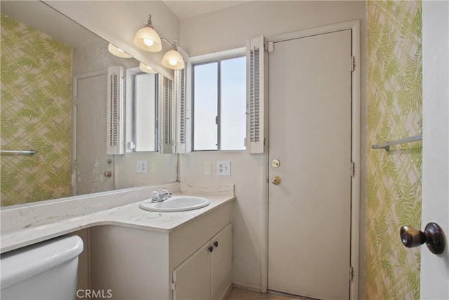 bathroom featuring wallpapered walls, toilet, and vanity