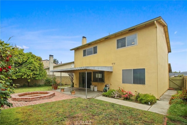 back of property with a patio, stucco siding, a fenced backyard, a chimney, and a lawn