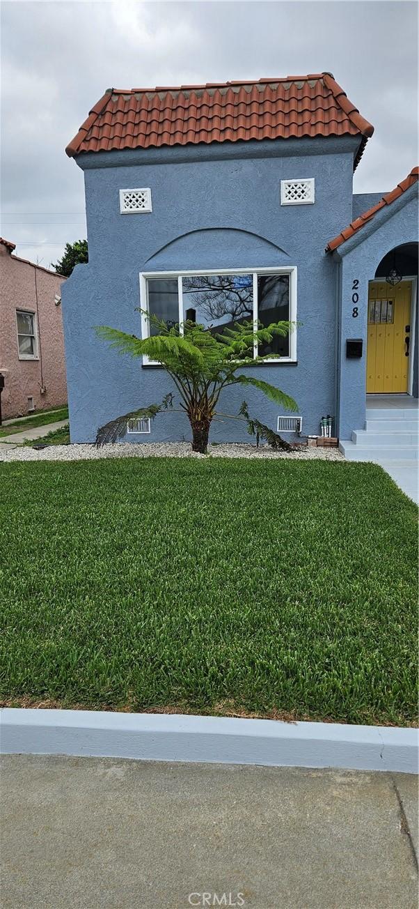 208 S Burris Ave, Compton, CA 90221 - view of property exterior featuring stucco siding, a tile roof, and a lawn