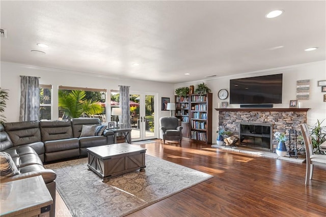 living room featuring wood finished floors, a fireplace, crown molding, visible vents, and recessed lighting