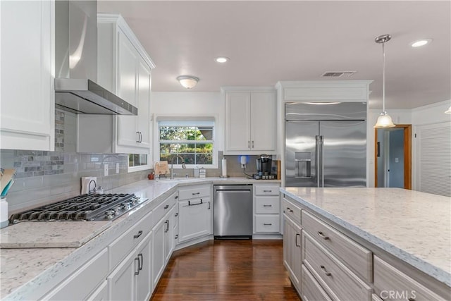 kitchen featuring visible vents, a sink, wall chimney exhaust hood, white cabinets, and appliances with stainless steel finishes