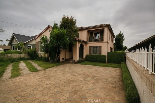rear view of property with stucco siding, fence, and a balcony