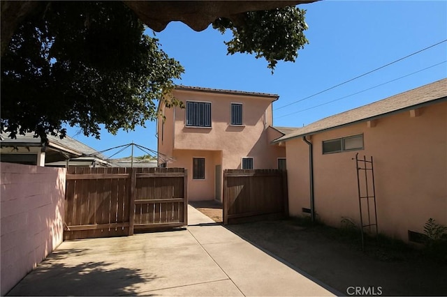 606 W 57th St, Los Angeles, CA 90037 - back of property with stucco siding, a gate, and a patio area