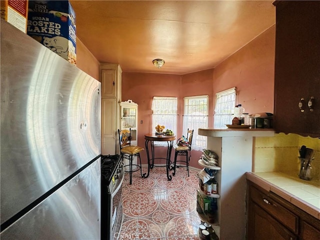 606 W 57th St, Los Angeles, CA 90037 - kitchen with appliances with stainless steel finishes, tile countertops, and light tile patterned floors