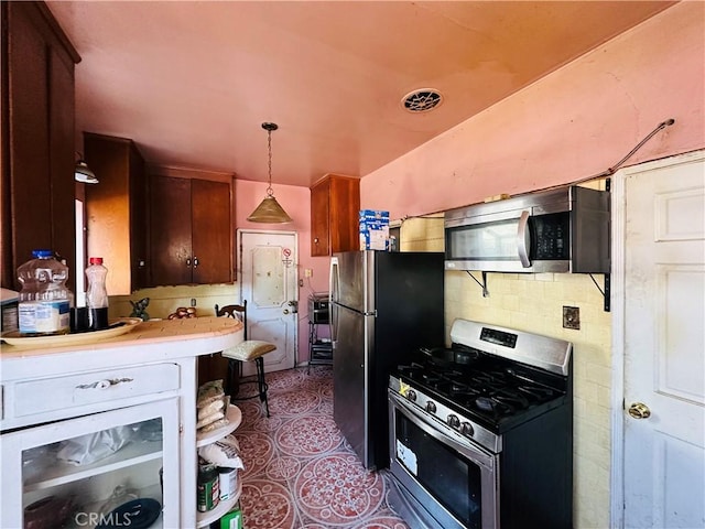 606 W 57th St, Los Angeles, CA 90037 - kitchen featuring stainless steel appliances, beverage cooler, light countertops, decorative light fixtures, and tile patterned floors