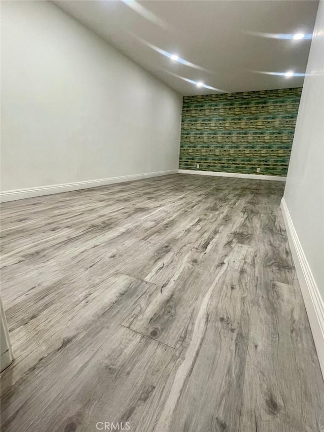 finished below grade area with baseboards and wood finished floors