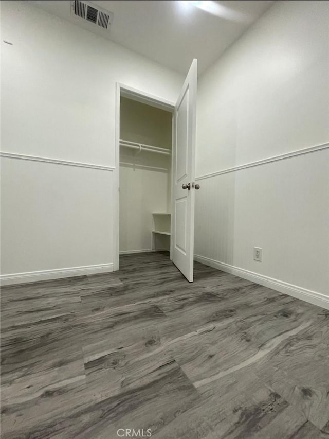 unfurnished bedroom featuring baseboards, a closet, visible vents, and wood finished floors