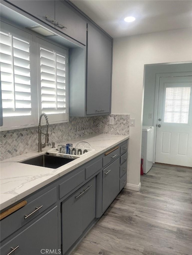 kitchen with gray cabinets, washer / clothes dryer, and a sink