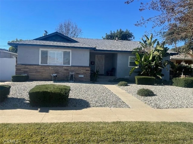 view of front of house with stone siding, stucco siding, and roof with shingles