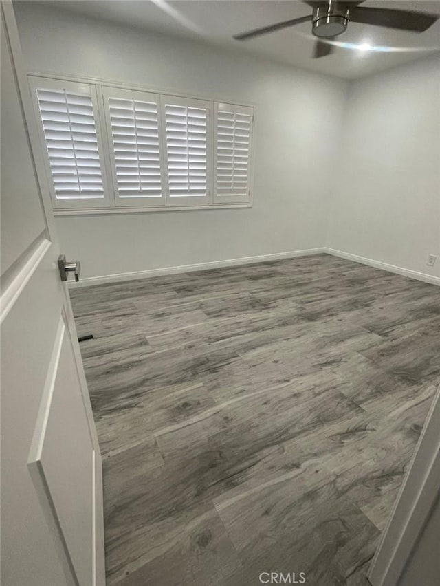 spare room with a ceiling fan, baseboards, and wood finished floors