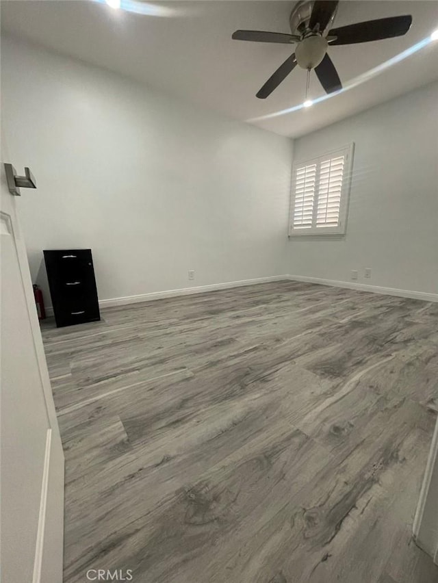 spare room with baseboards, ceiling fan, and wood finished floors