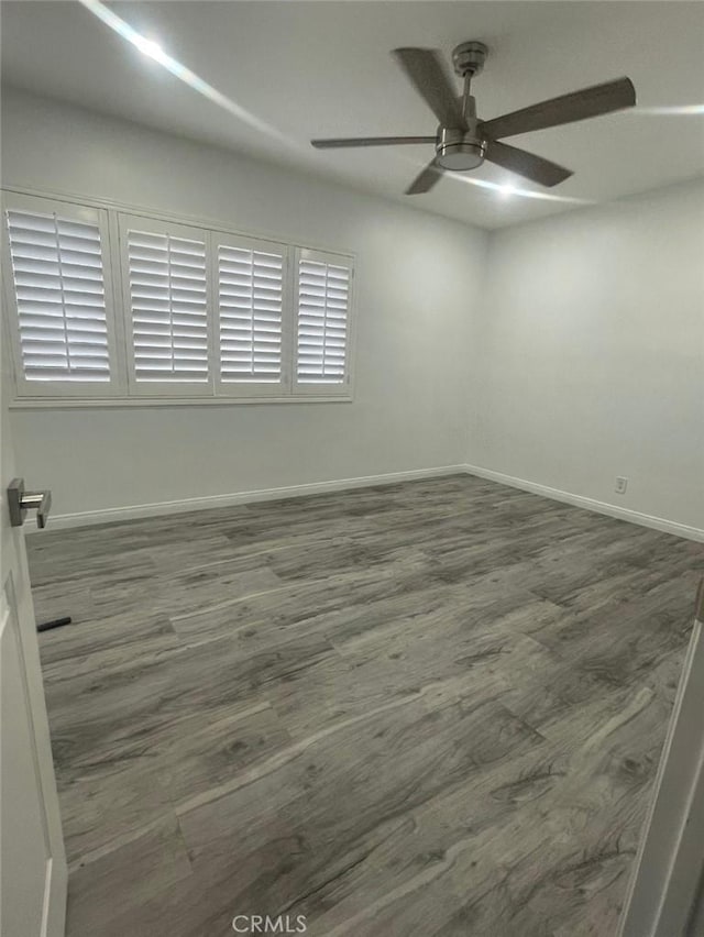 spare room featuring baseboards, ceiling fan, and wood finished floors
